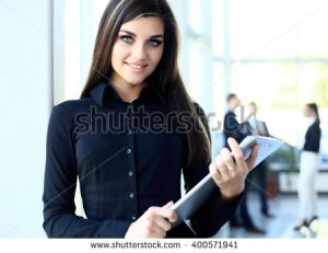 stock-photo-business-woman-standing-in-foreground-with-a-tablet-in-her-hands-her-co-workers-discussing-400571941